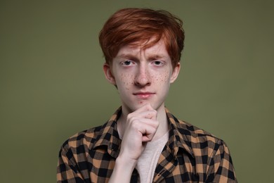 Photo of Cute teenage boy with freckles on dark green background