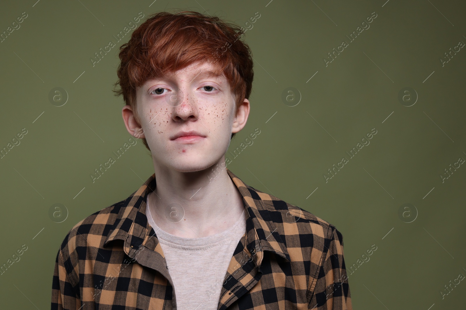 Photo of Portrait of cute teenage boy with freckles on dark green background