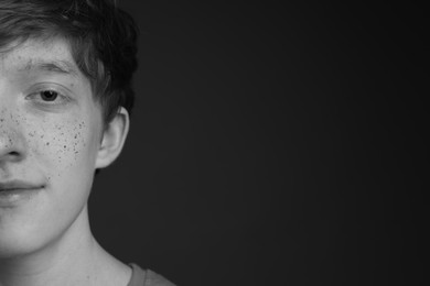 Photo of Teenage boy with freckles on dark background, black and white effect. Space for text