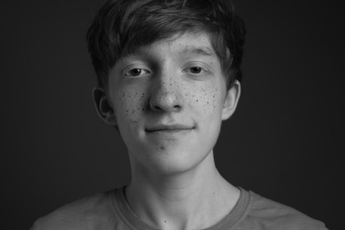 Photo of Teenage boy with freckles on dark background, black and white effect