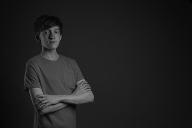 Photo of Teenage boy with freckles on dark background, black and white effect. Space for text