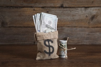 Photo of Burlap sack with dollar banknotes on wooden table