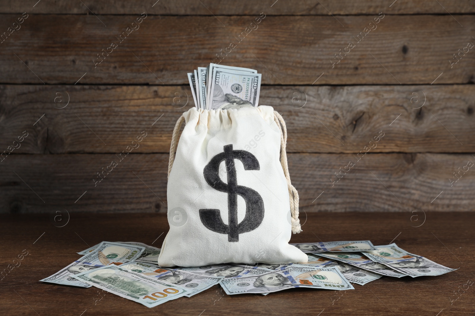 Photo of Burlap sack with dollar banknotes on wooden table