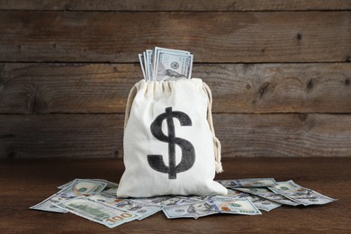 Photo of Burlap sack with dollar banknotes on wooden table