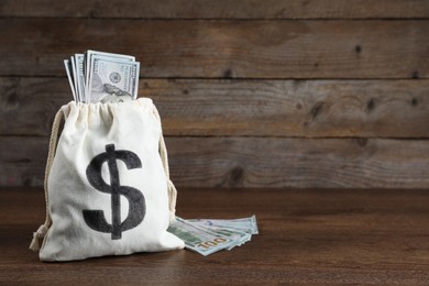 Photo of Dollar banknotes in burlap sack on wooden table, space for text