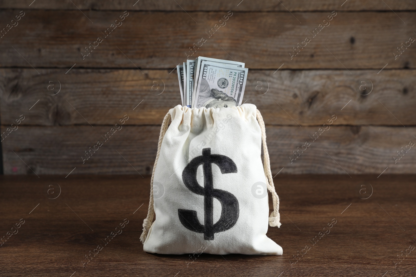 Photo of Dollar banknotes in burlap sack on wooden table