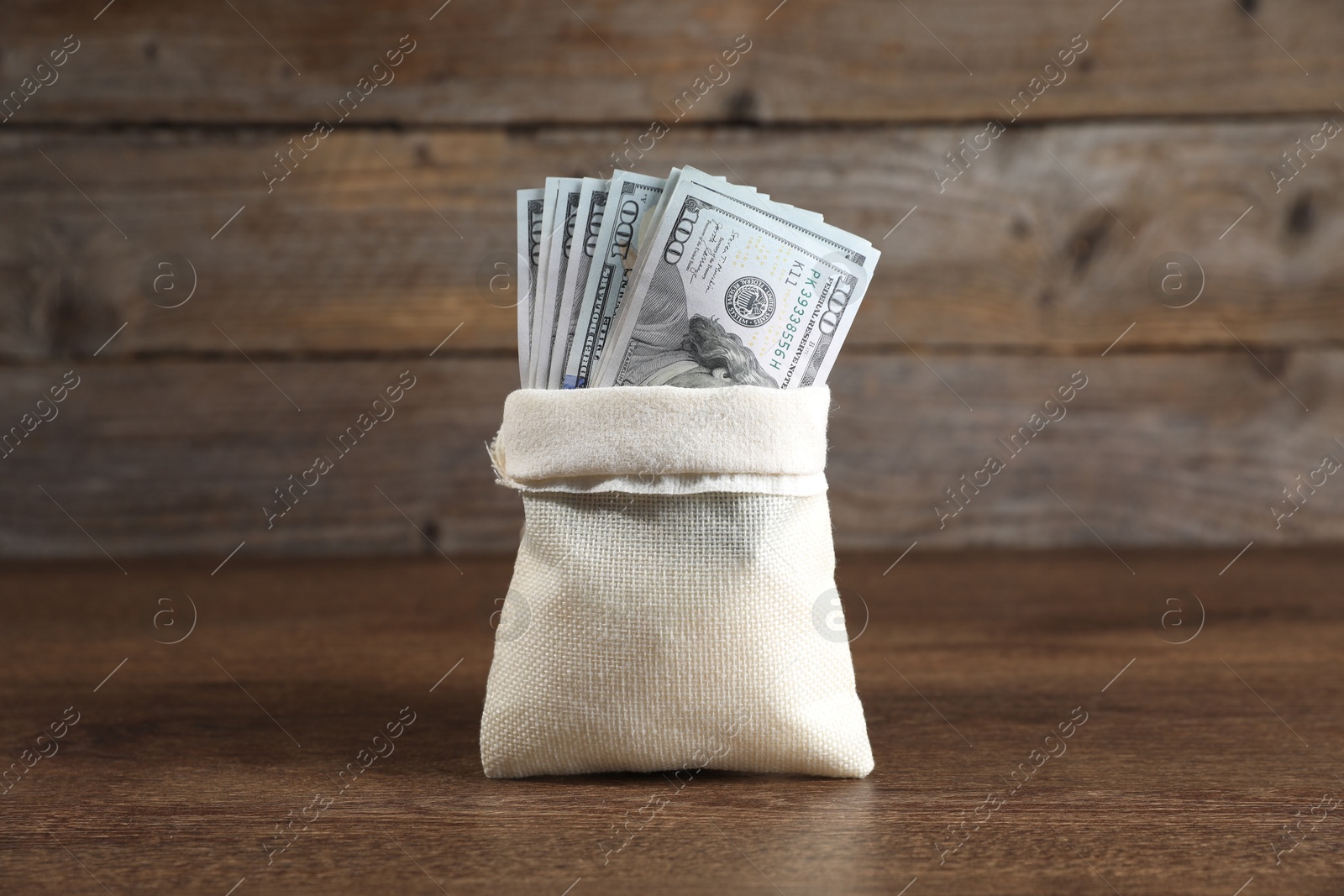 Photo of Dollar banknotes in burlap sack on wooden table