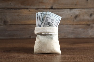 Photo of Dollar banknotes in burlap sack on wooden table