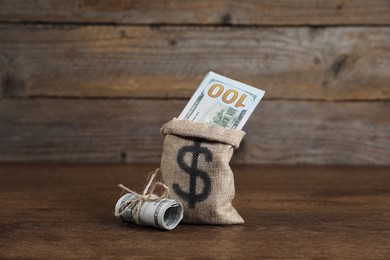 Photo of Burlap sack with dollar banknotes on wooden table