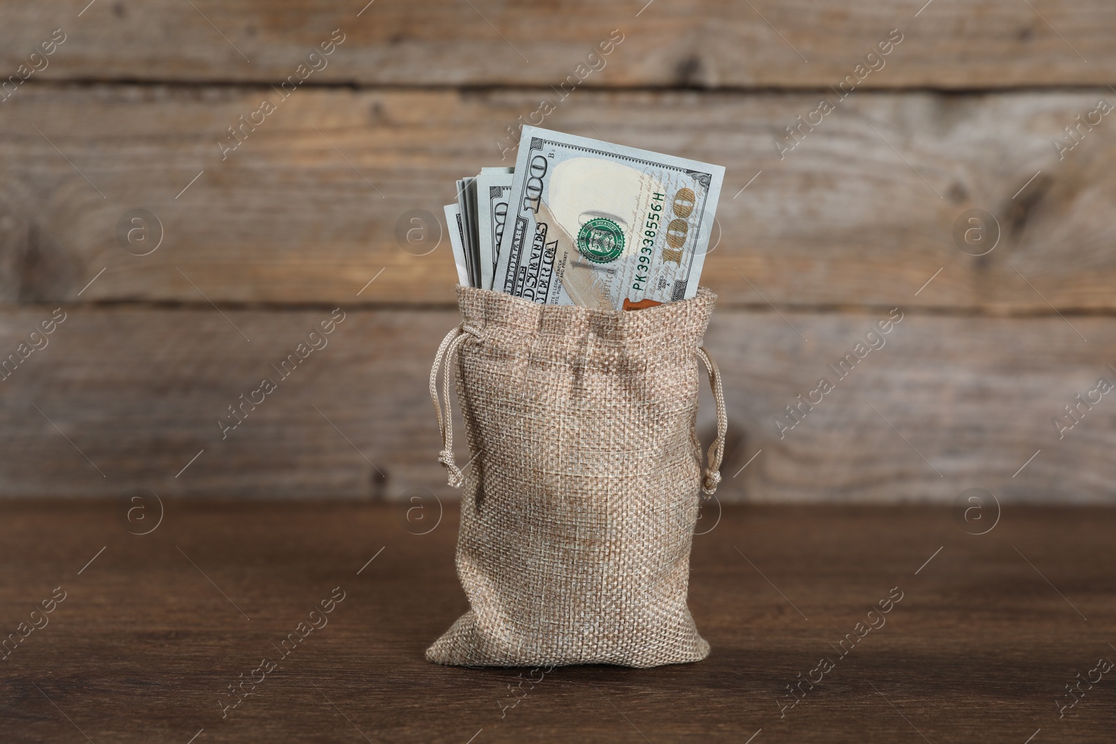 Photo of Dollar banknotes in burlap sack on wooden table