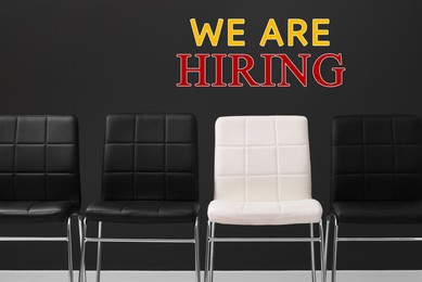 Image of We are hiring. White chair among black ones indoors. Human resource, recruitment concept