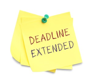 Image of Paper note with text Deadline Extended attached to white wall