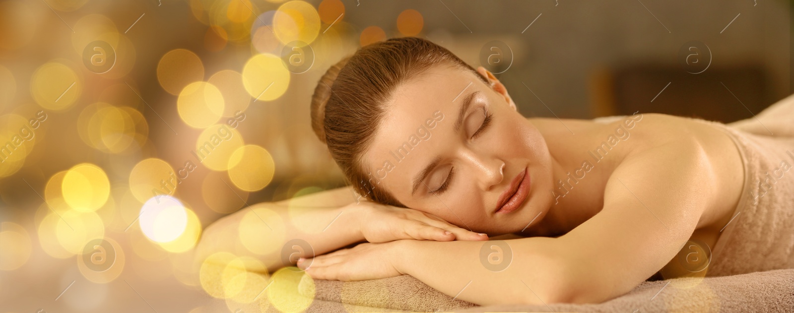 Image of Beautiful young woman relaxing on massage table in spa salon, bokeh effect. Banner design