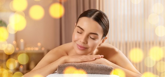 Image of Beautiful young woman relaxing on massage table in spa salon, bokeh effect. Banner design