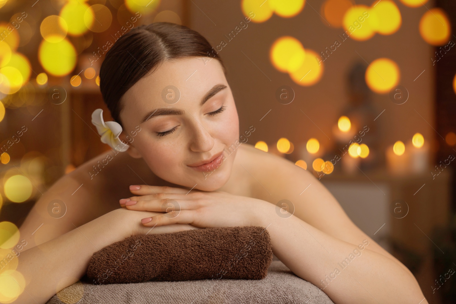 Image of Beautiful young woman relaxing on massage table in spa salon, bokeh effect