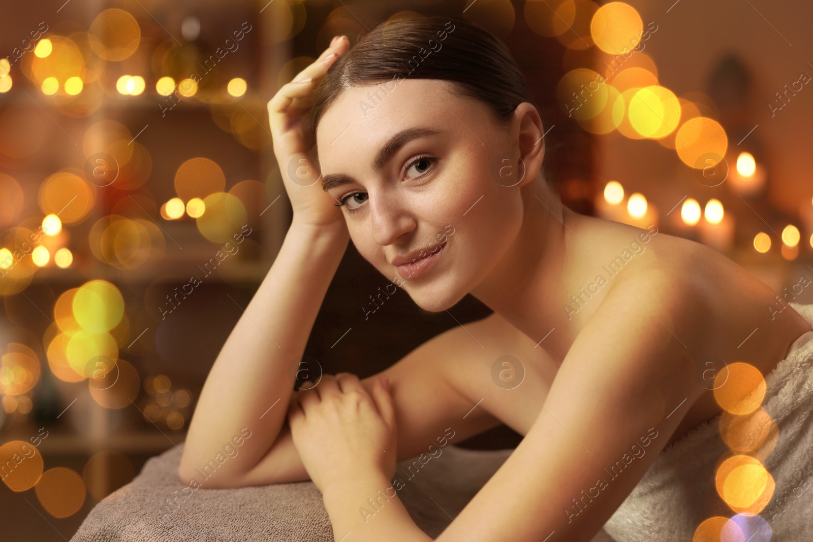 Image of Beautiful young woman relaxing on massage table in spa salon, bokeh effect