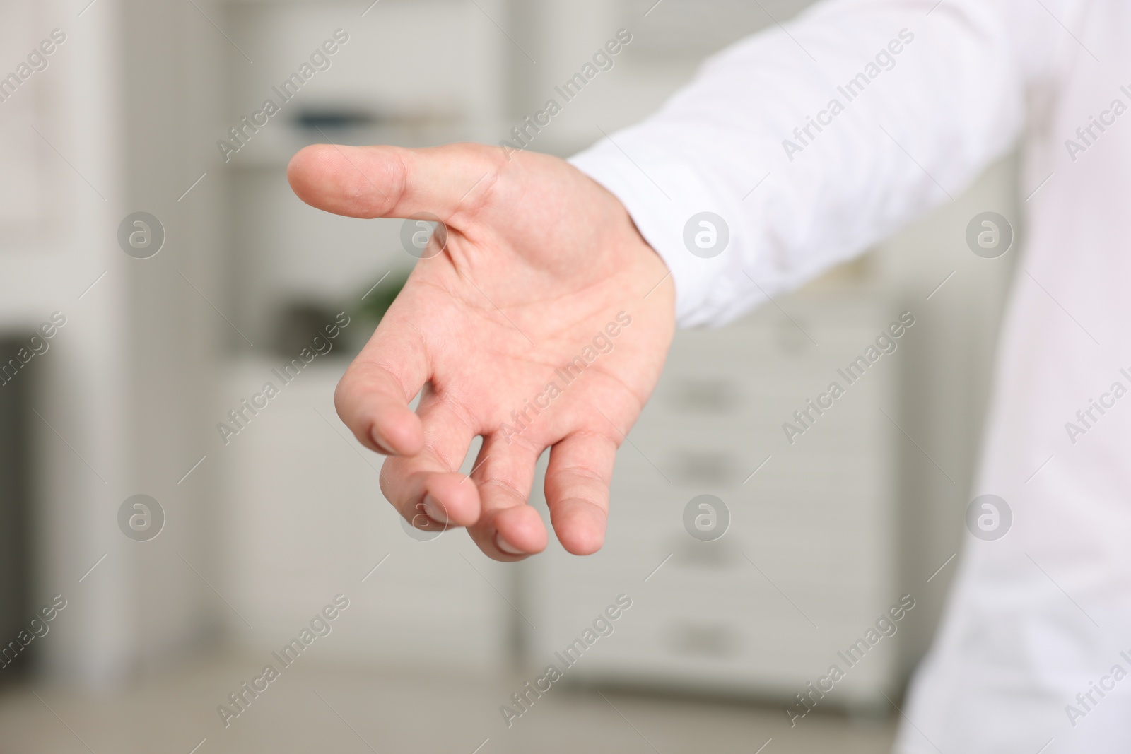 Photo of Offering help. Man reaching his hand indoors, closeup