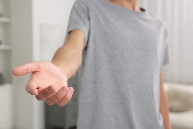 Photo of Offering help. Man reaching his hand indoors, closeup