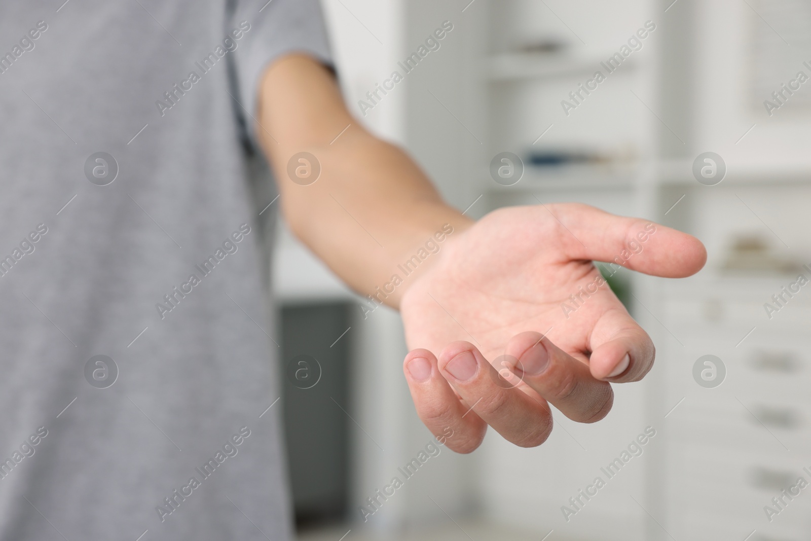 Photo of Offering help. Man reaching his hand indoors, closeup