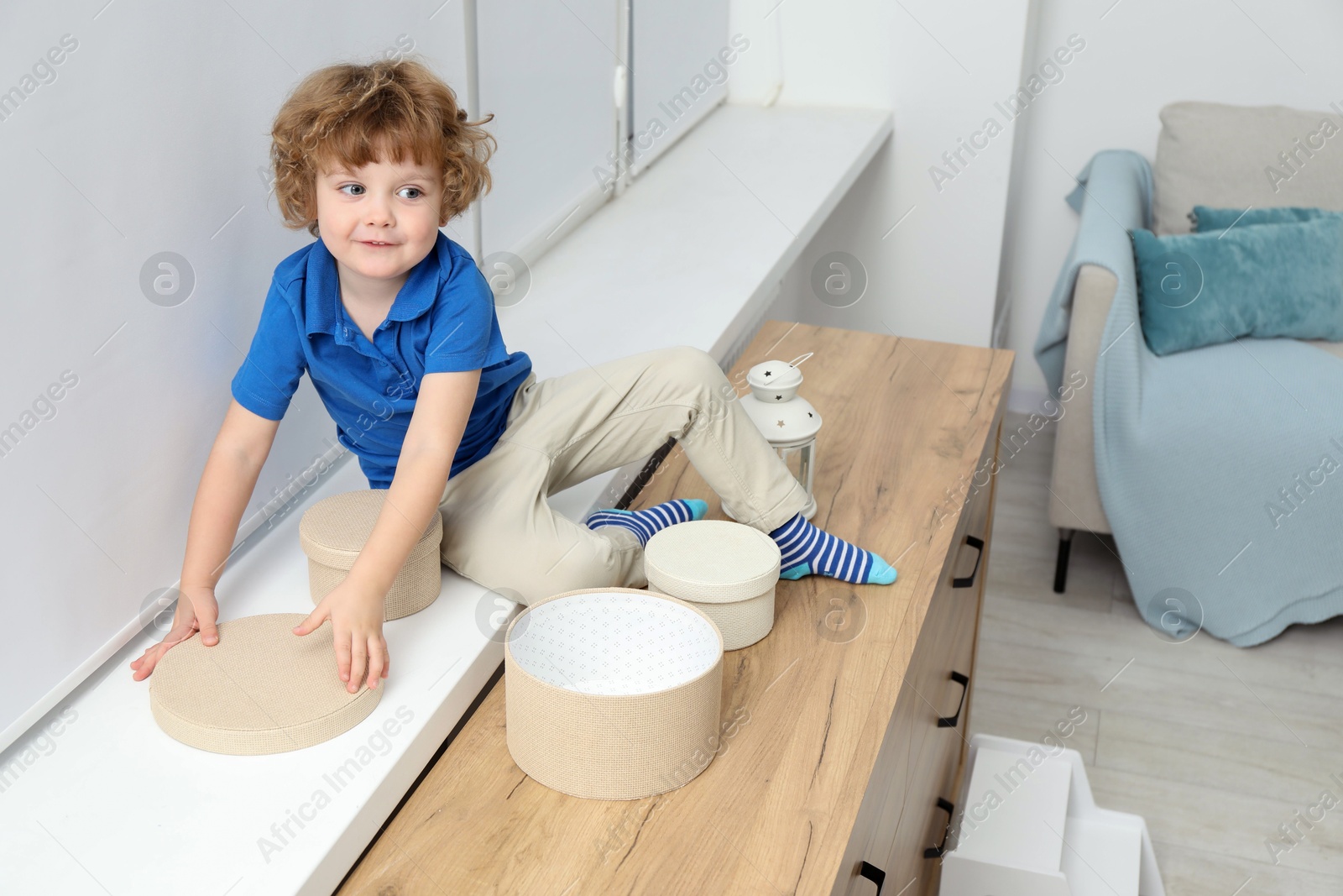 Photo of Little boy with boxes on window sill at home