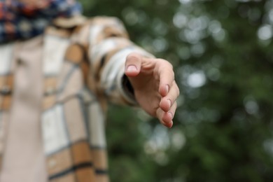 Photo of Offering help. Man reaching his hand outdoors, closeup