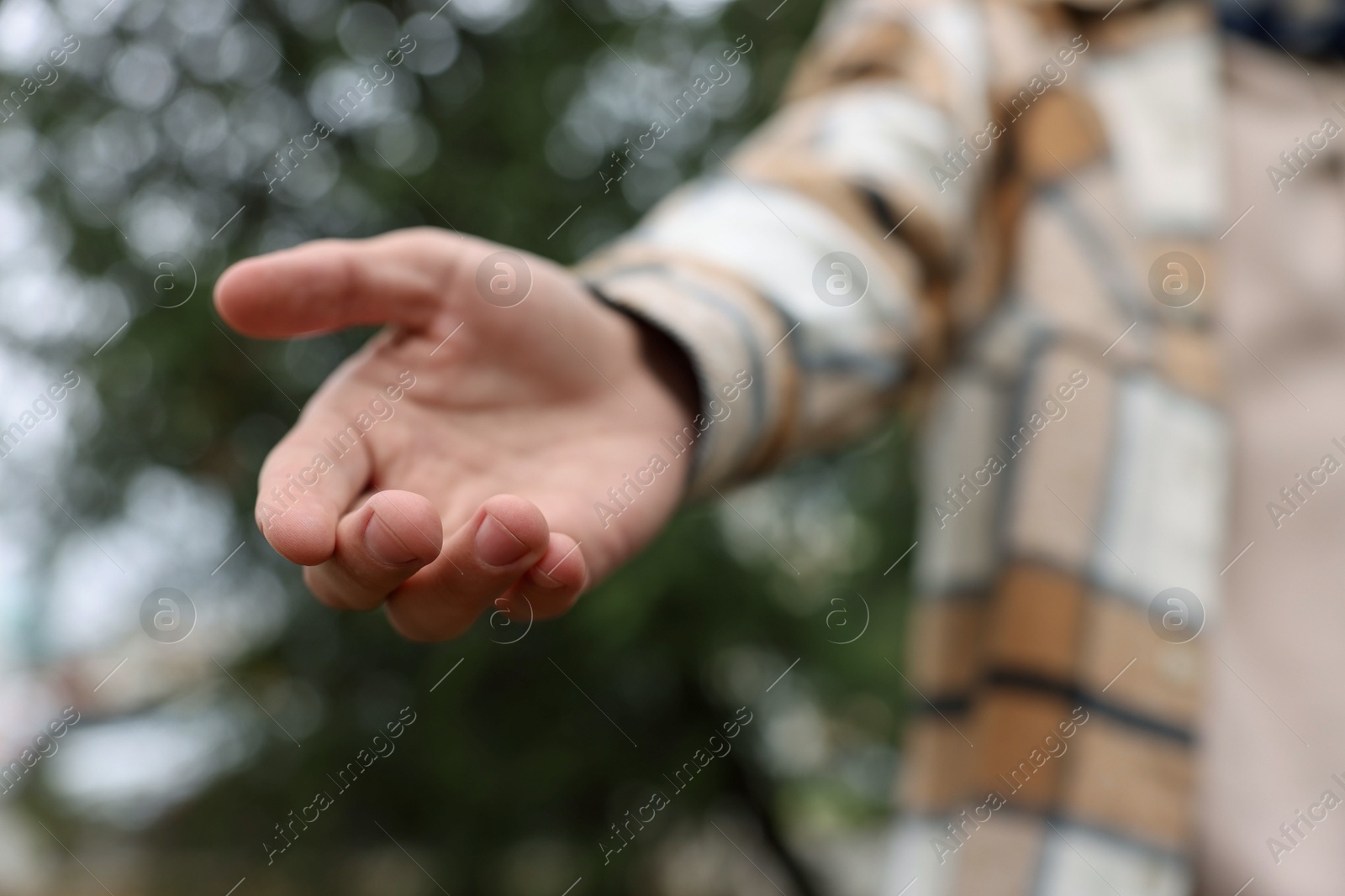 Photo of Offering help. Man reaching his hand outdoors, closeup