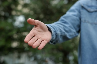 Photo of Offering help. Man reaching his hand outdoors, closeup