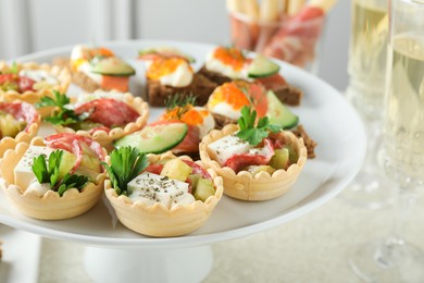 Photo of Many different tasty canapes and wine on white table, closeup