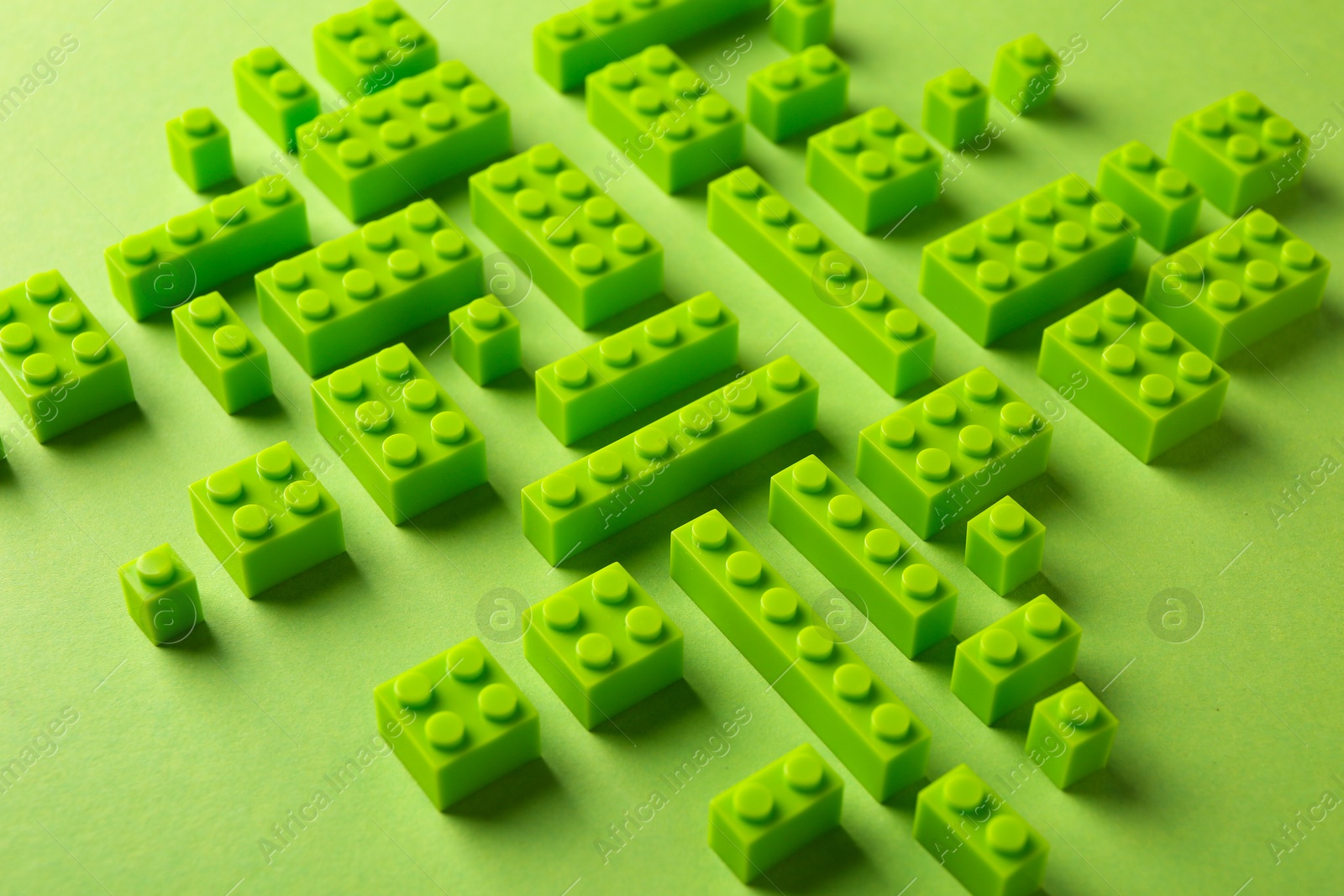 Photo of Constructor toy. Many building blocks on light green background