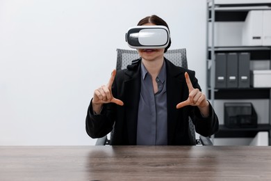 Photo of Woman using virtual reality headset in office