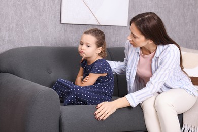 Photo of Resentful little girl and her mother at home. Family dispute