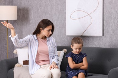 Photo of Resentful little girl and her mother arguing at home