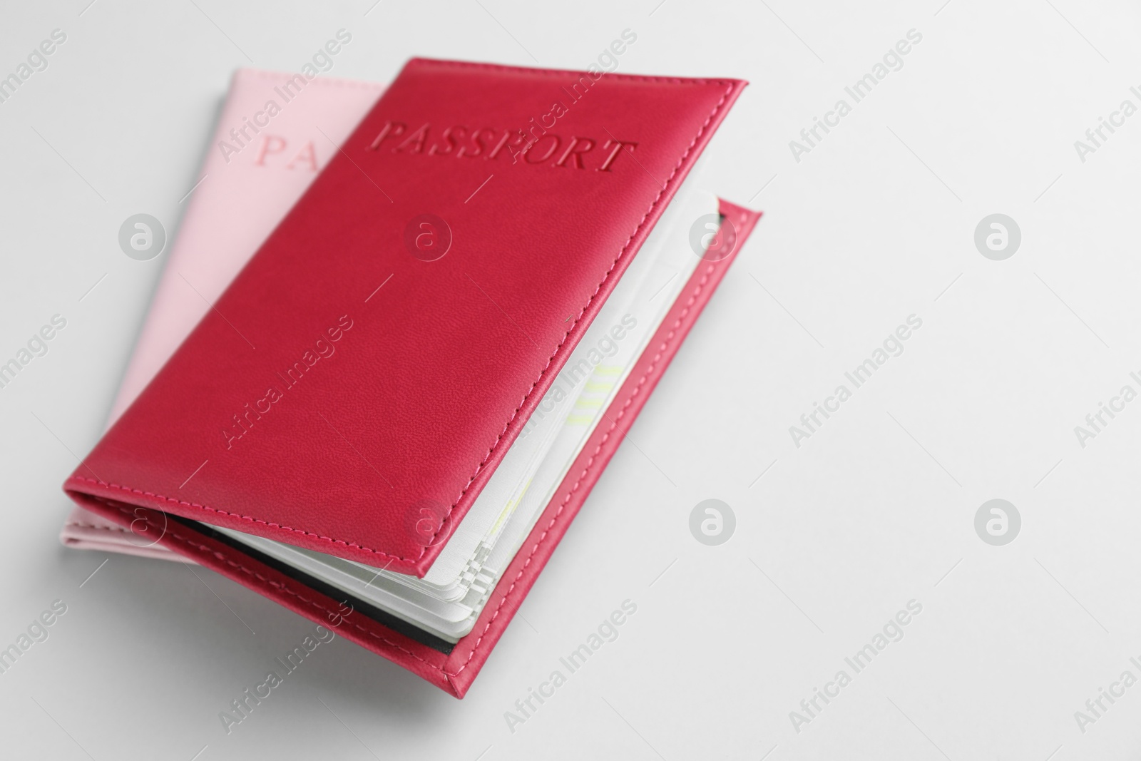 Photo of Passports in color covers on light background, closeup. Space for text