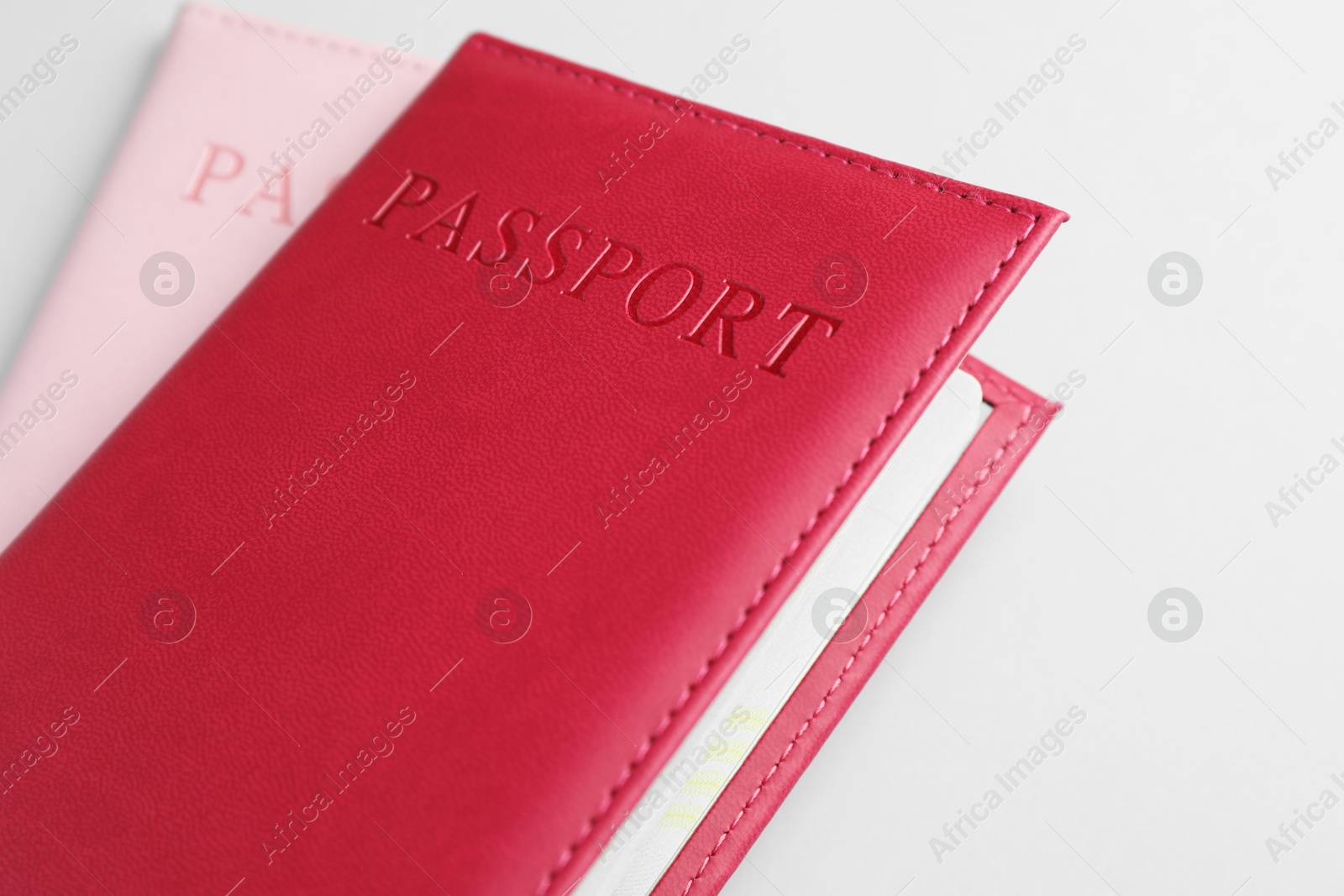 Photo of Passports in color covers on light background, closeup