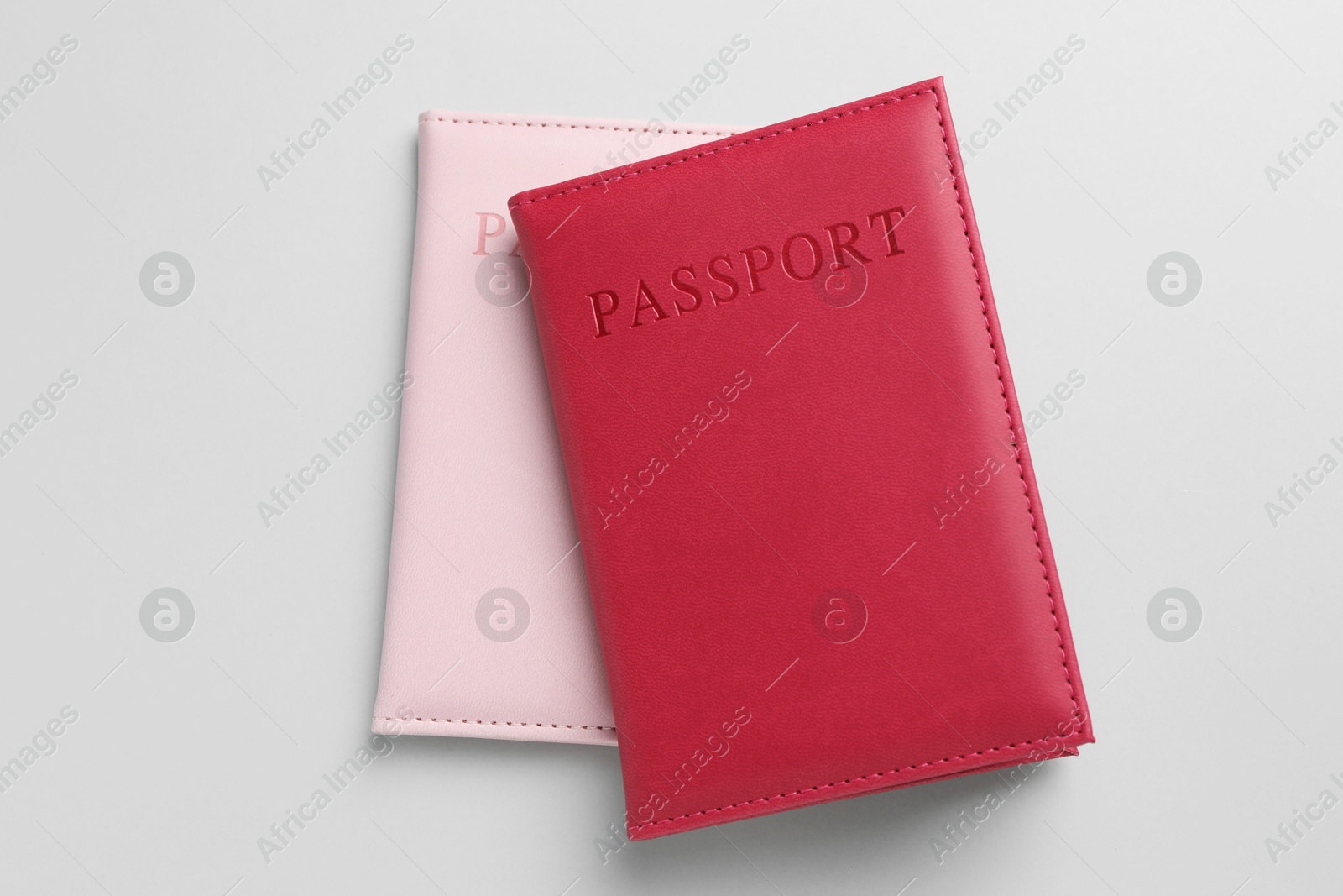 Photo of Passports in color covers on light background, top view