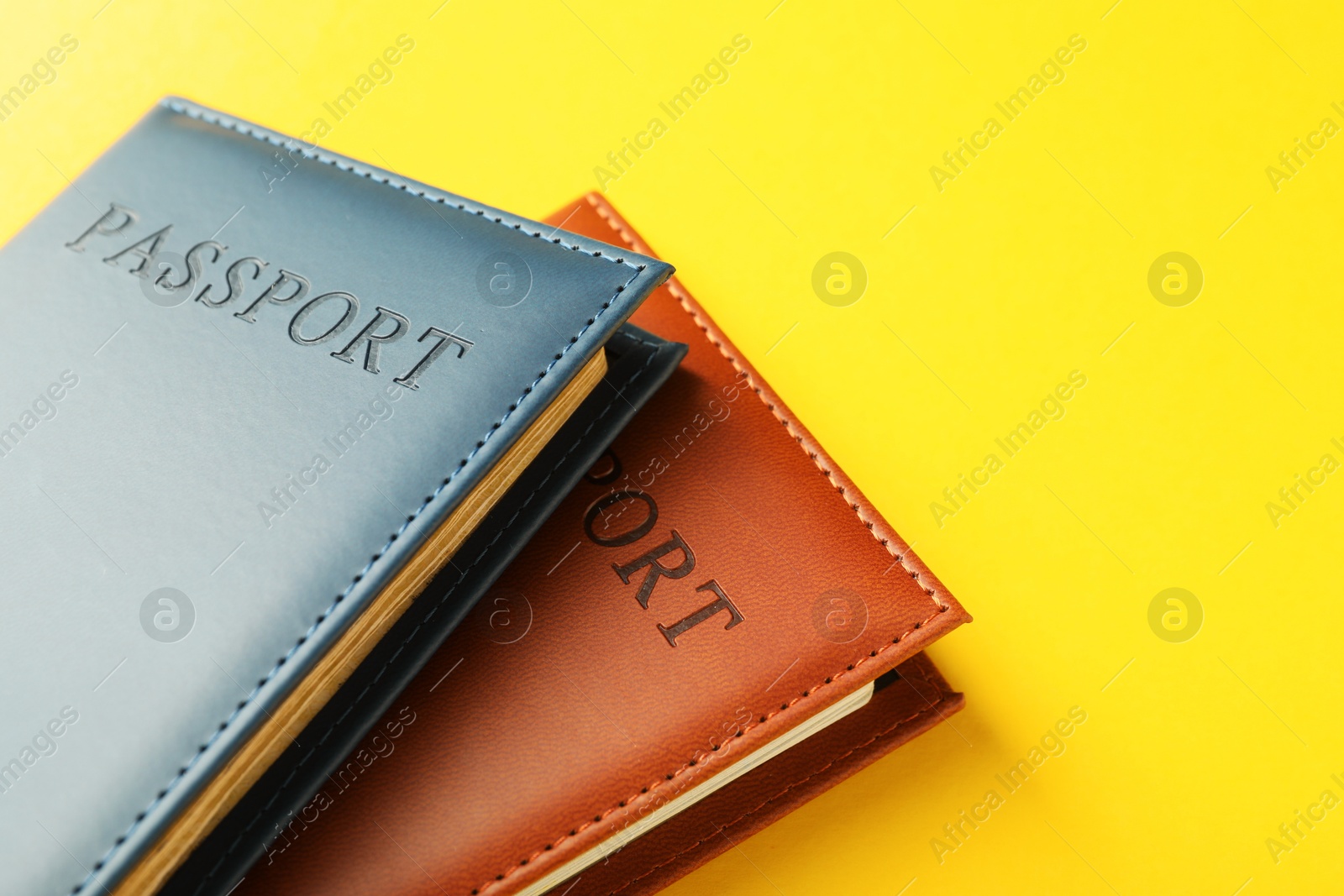 Photo of Passports in color covers on yellow background, closeup. Space for text