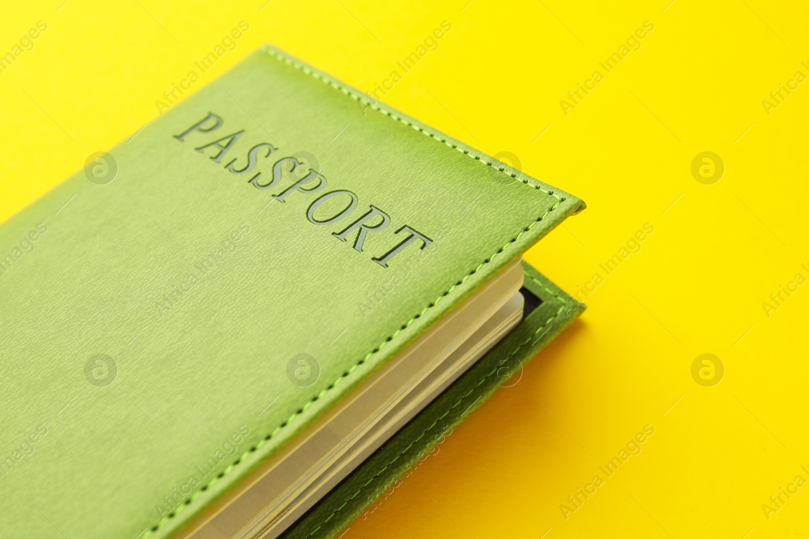 Photo of Passport in green cover on yellow background, closeup