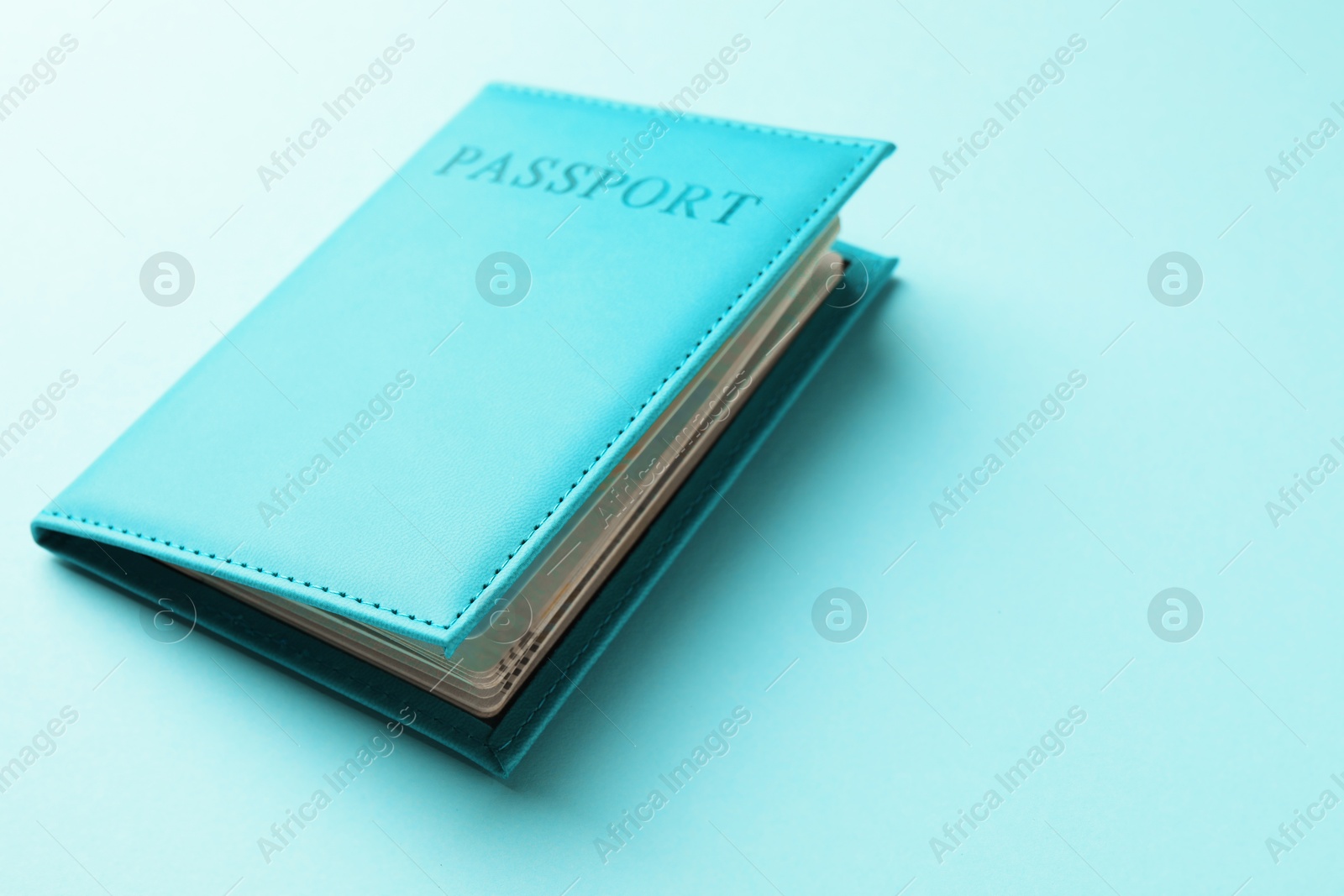 Photo of Passport in bright cover on light blue background, closeup. Space for text