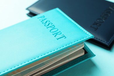 Photo of Passports in color covers on light blue background, closeup