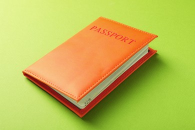 Photo of Passport in orange cover on green background, closeup