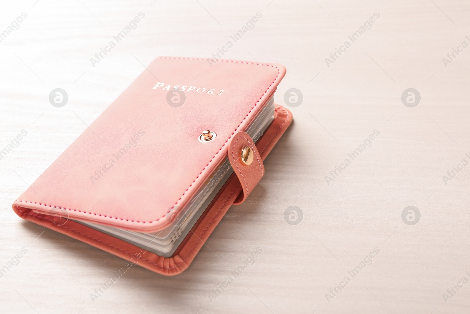 Photo of Passport in pink cover on white wooden table, space for text