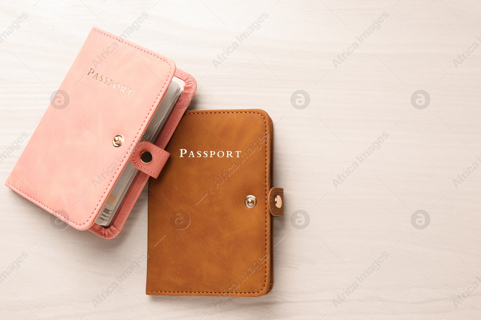 Photo of Two passports in bright covers on white wooden table, top view. Space for text