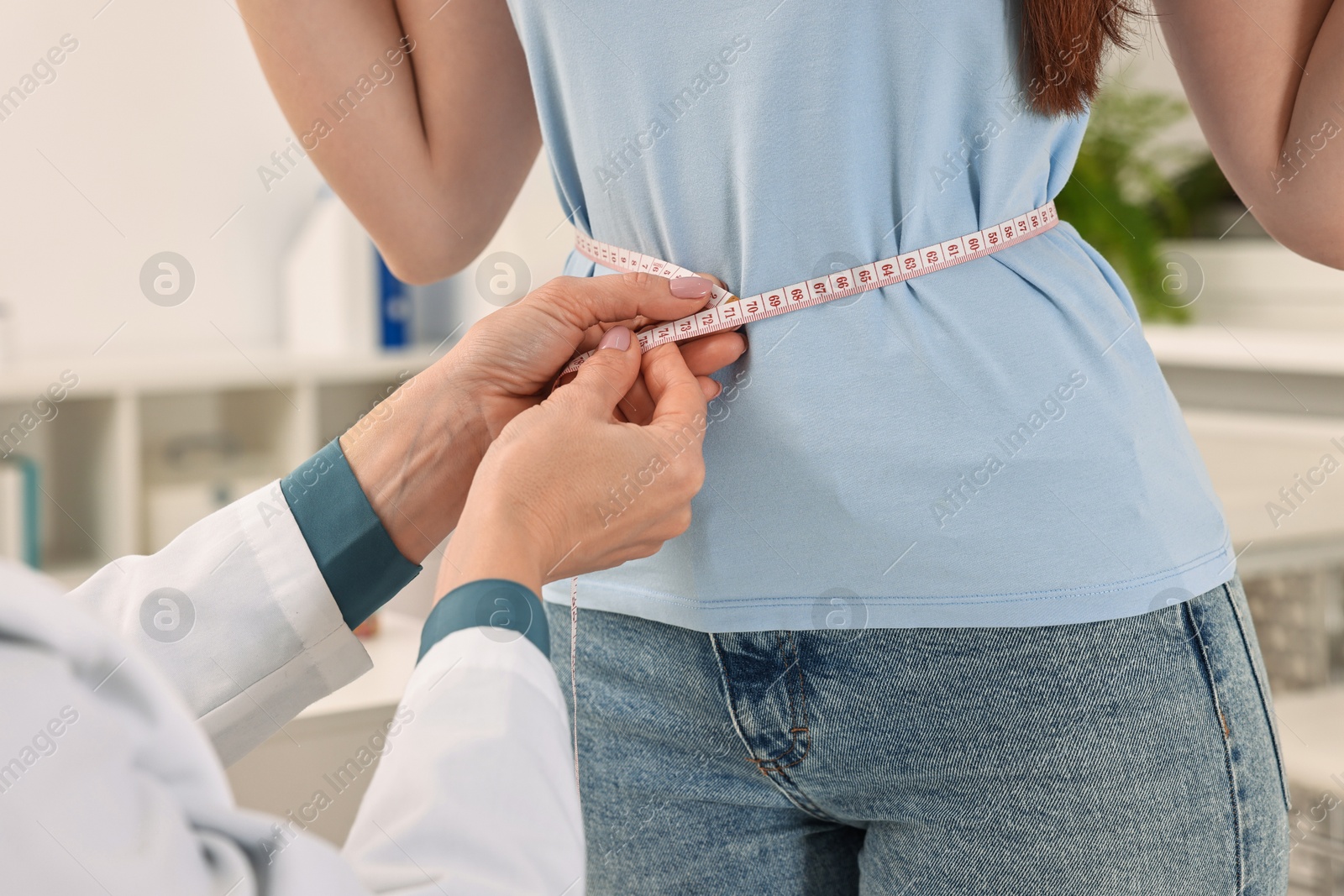 Photo of Weight loss. Nutritionist measuring patient's waist with tape in clinic, closeup