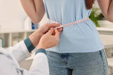 Photo of Weight loss. Nutritionist measuring patient's waist with tape in clinic, closeup