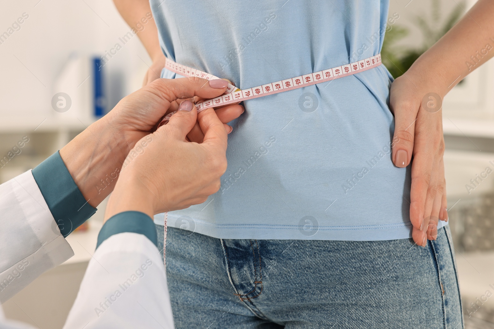 Photo of Weight loss. Nutritionist measuring patient's waist with tape in clinic, closeup