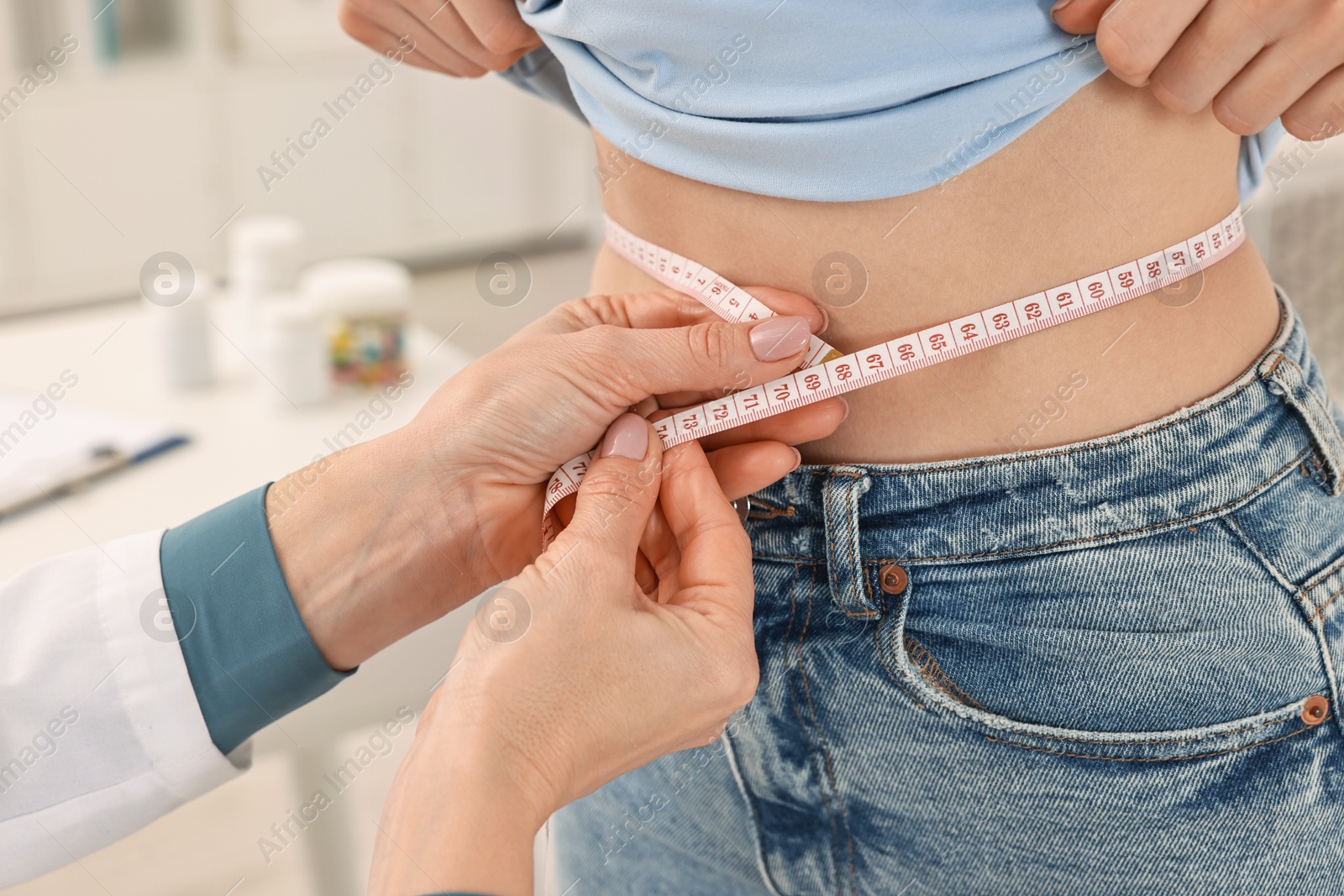 Photo of Weight loss. Nutritionist measuring patient's waist with tape in clinic, closeup