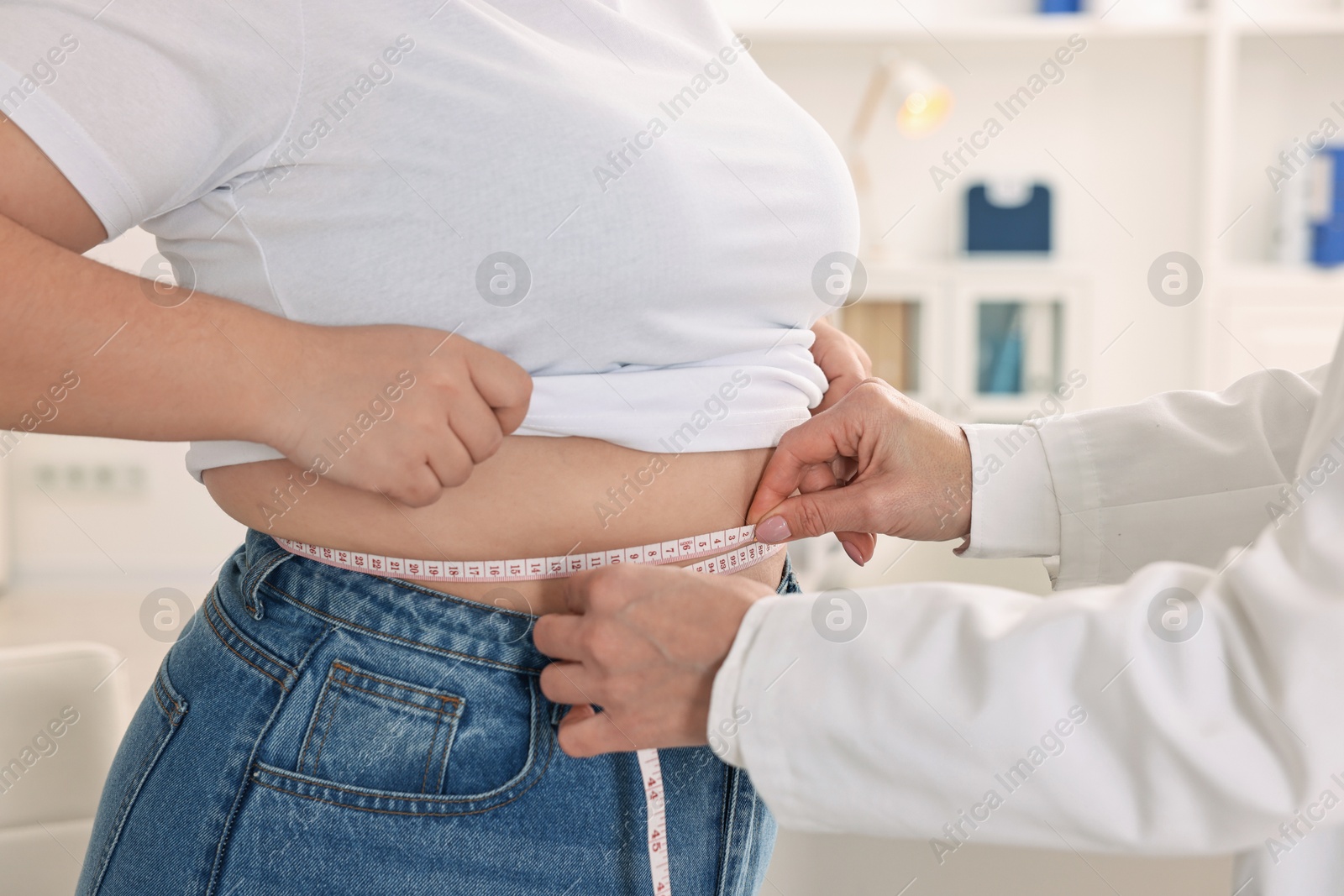 Photo of Weight loss. Nutritionist measuring patient's waist with tape in clinic, closeup