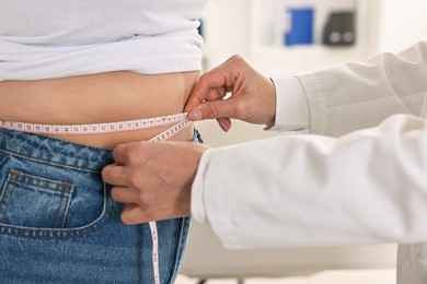 Photo of Weight loss. Nutritionist measuring patient's waist with tape in clinic, closeup