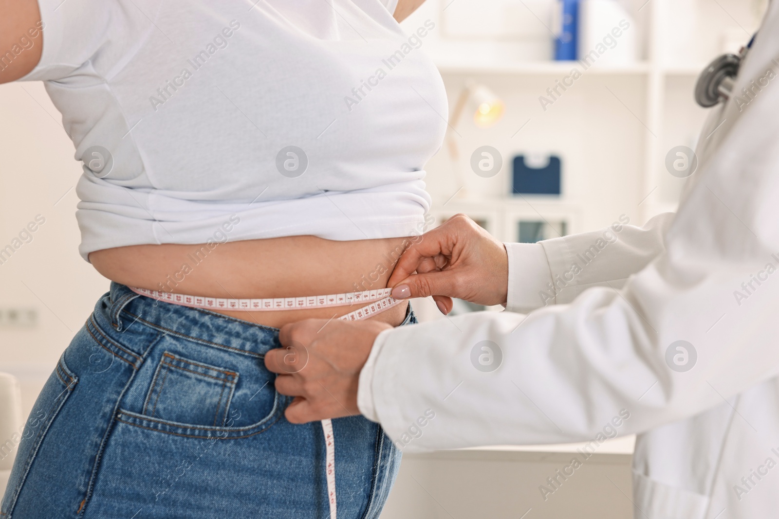 Photo of Weight loss. Nutritionist measuring patient's waist with tape in clinic, closeup