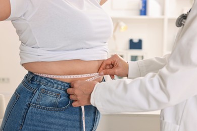 Photo of Weight loss. Nutritionist measuring patient's waist with tape in clinic, closeup